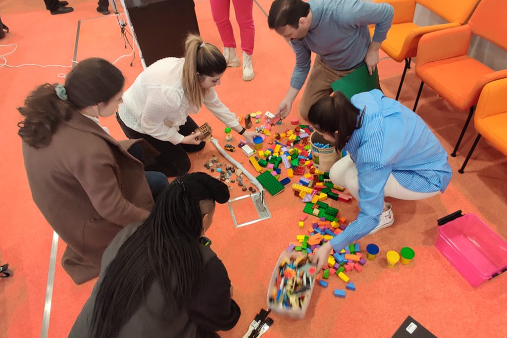 Five people building with Lego building blocks.